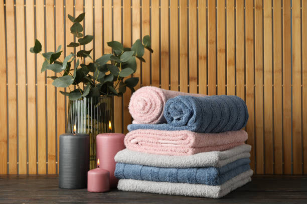 Towels, candles and eucalyptus on wooden table against bamboo background, space for text